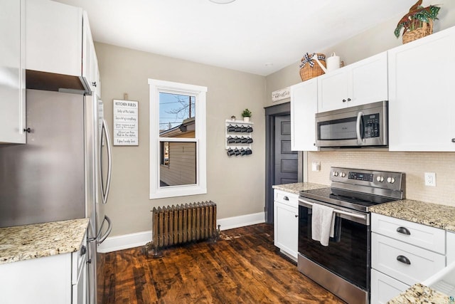 kitchen with dark wood-type flooring, backsplash, stainless steel appliances, radiator, and white cabinets