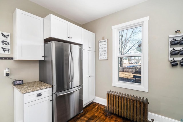 kitchen with white cabinets, radiator, freestanding refrigerator, and baseboards