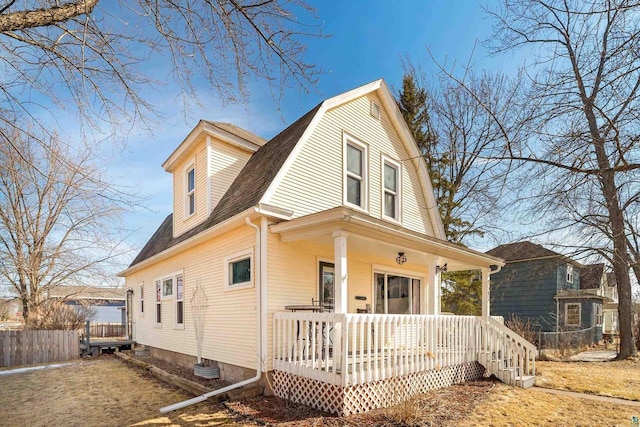 exterior space with a gambrel roof, roof with shingles, and fence