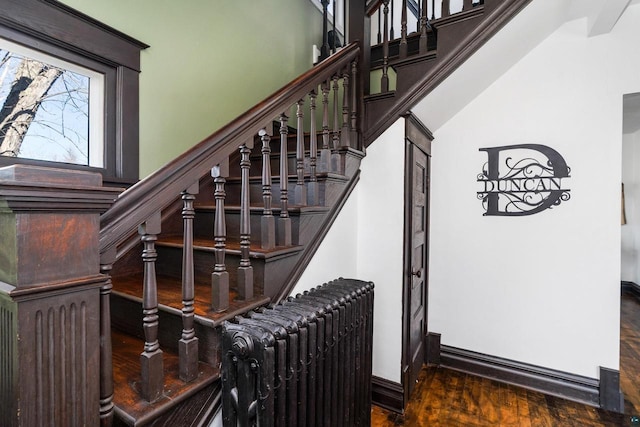 stairs featuring radiator, wood finished floors, and baseboards