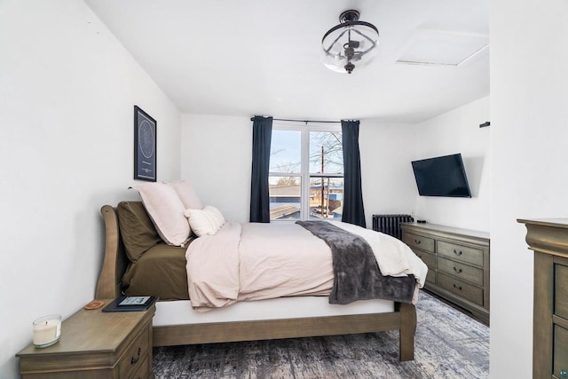 bedroom featuring radiator, attic access, and wood finished floors