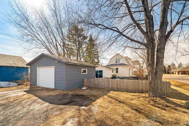 detached garage featuring driveway and fence