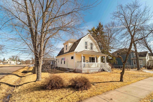 view of front of home with a porch, fence, and a gambrel roof