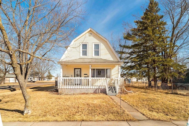 dutch colonial with a gambrel roof, covered porch, a front lawn, and fence