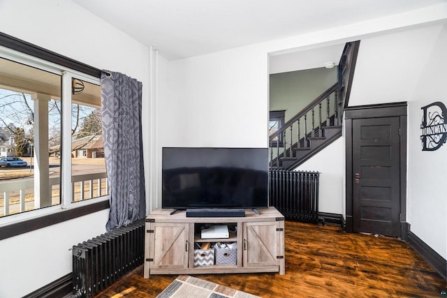 living area with stairs, baseboards, dark wood finished floors, and radiator heating unit