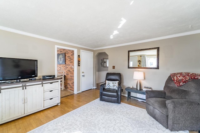 living area featuring light wood-style flooring, arched walkways, and ornamental molding