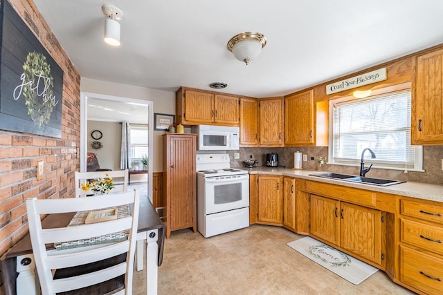 kitchen featuring a sink, white appliances, a healthy amount of sunlight, and light countertops