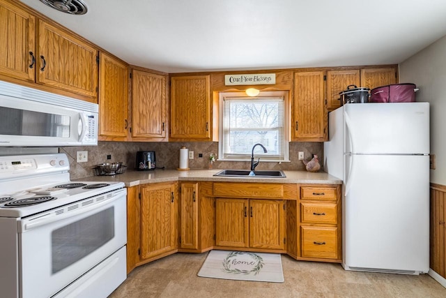 kitchen with white appliances, light countertops, brown cabinets, and a sink