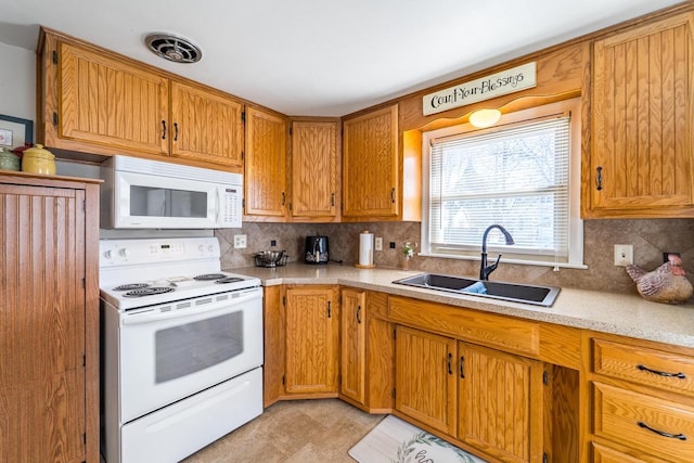 kitchen featuring tasteful backsplash, white appliances, light countertops, and a sink