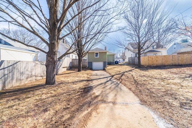 view of yard featuring an attached garage, fence, and driveway