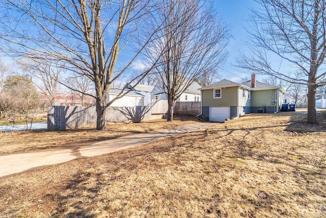 view of yard with an attached garage, driveway, and fence