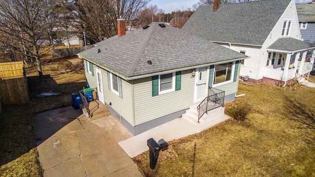 bungalow-style house with driveway, roof with shingles, a chimney, and fence