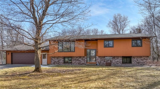 bi-level home featuring driveway, a front yard, a garage, brick siding, and a chimney