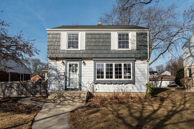 colonial home with a gambrel roof, a chimney, and fence