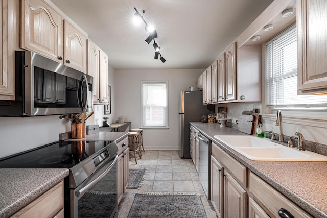 kitchen with light brown cabinetry, appliances with stainless steel finishes, and a sink