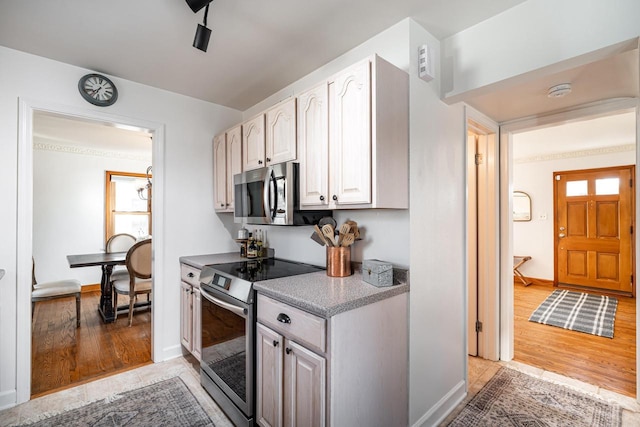 kitchen with appliances with stainless steel finishes, light countertops, light wood-type flooring, and baseboards