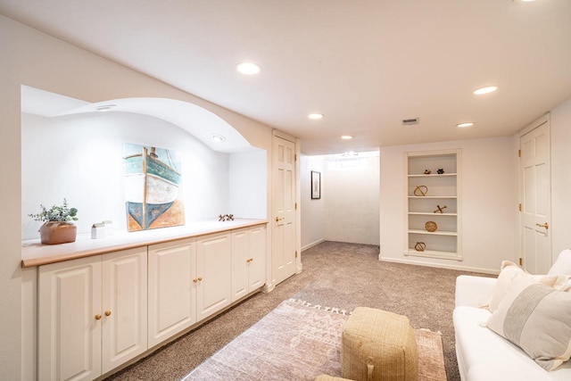 living area featuring recessed lighting, visible vents, built in shelves, and light colored carpet