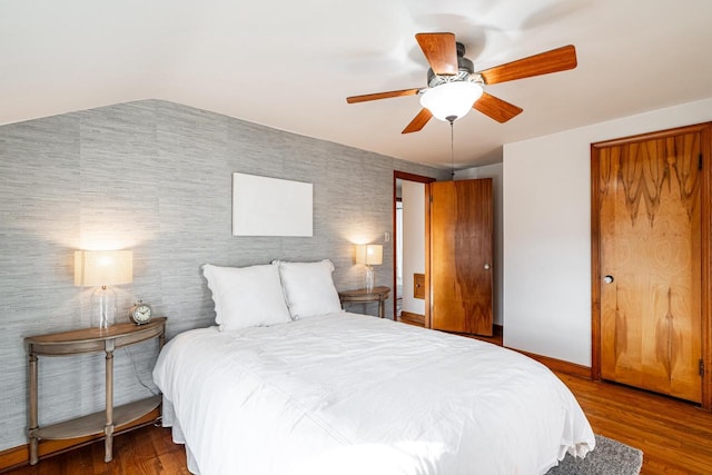 bedroom with wallpapered walls, a ceiling fan, baseboards, and wood finished floors