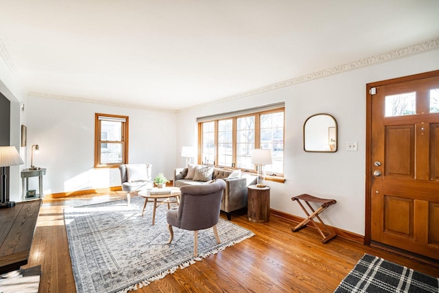 living room with crown molding, baseboards, and wood finished floors