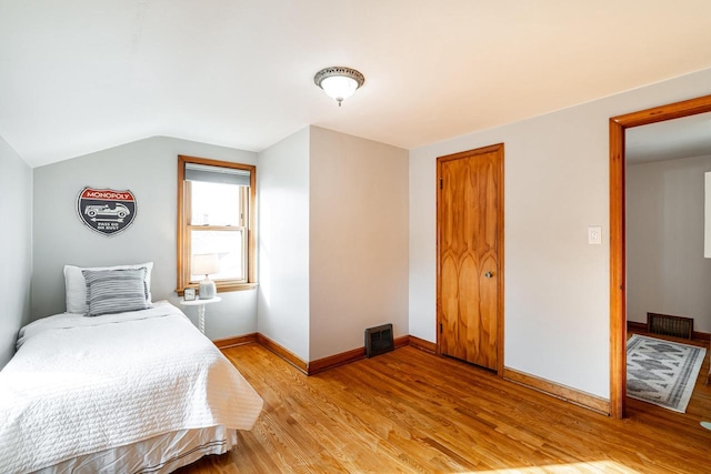 bedroom with visible vents, baseboards, lofted ceiling, a closet, and light wood-type flooring