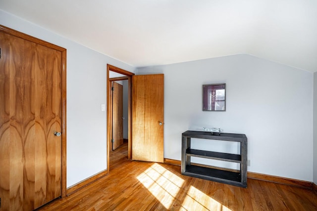 unfurnished bedroom featuring vaulted ceiling, baseboards, and wood finished floors