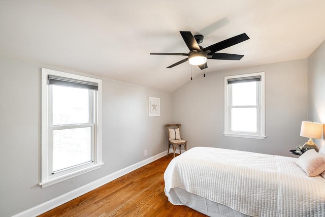 bedroom with a ceiling fan, vaulted ceiling, wood finished floors, and baseboards