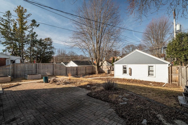 view of yard featuring a patio area, a fenced backyard, and a vegetable garden