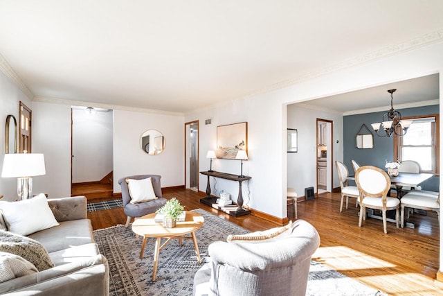 living room with ornamental molding, baseboards, an inviting chandelier, and wood finished floors