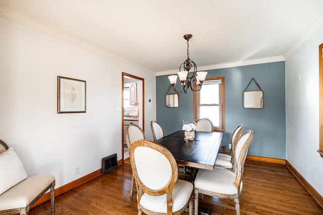 dining space featuring a chandelier, crown molding, baseboards, and wood finished floors