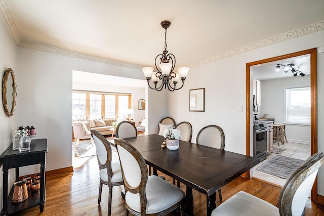 dining space featuring a chandelier, ornamental molding, baseboards, and wood finished floors