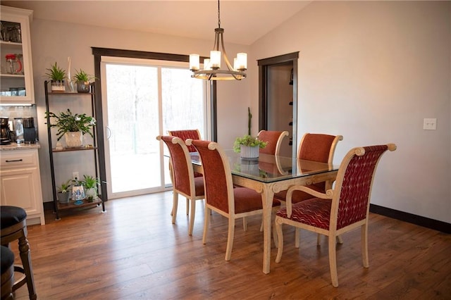 dining room with a chandelier, plenty of natural light, wood finished floors, and vaulted ceiling