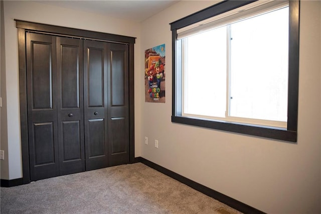 unfurnished bedroom with visible vents, baseboards, a closet, and carpet floors