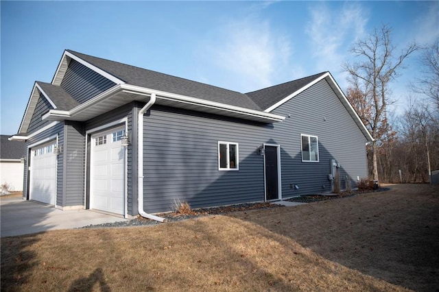 view of side of home with a lawn, concrete driveway, a garage, and roof with shingles