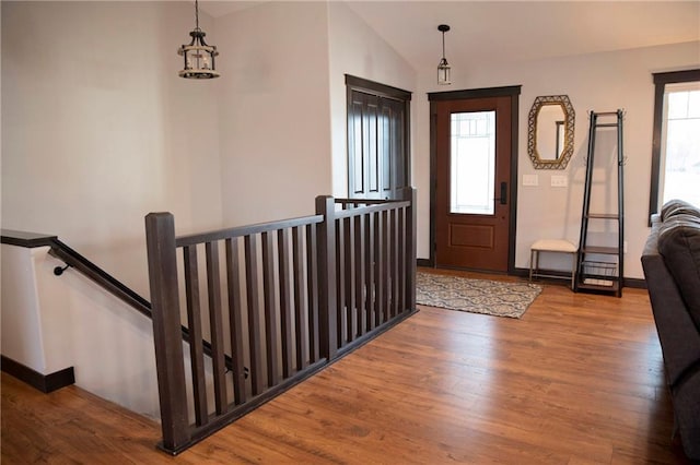 foyer with baseboards, lofted ceiling, and wood finished floors