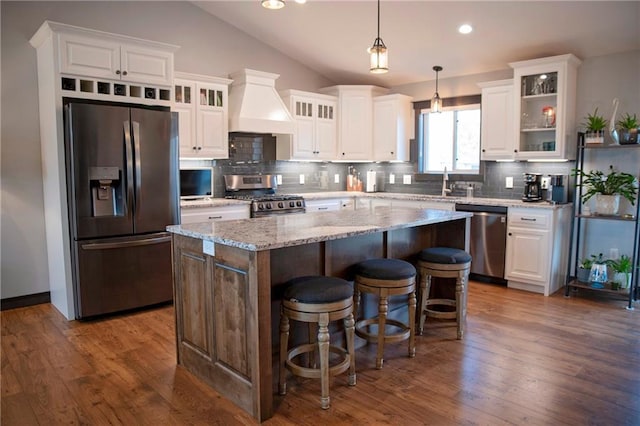 kitchen with a kitchen island, premium range hood, lofted ceiling, white cabinets, and stainless steel appliances