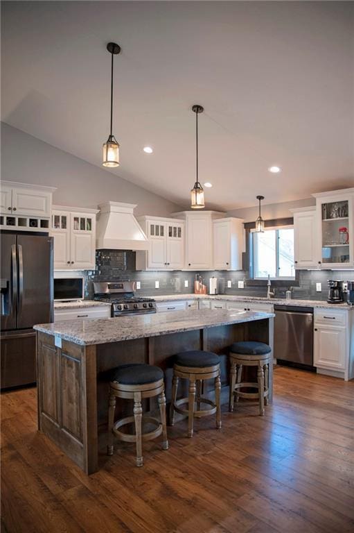 kitchen with a kitchen island, dark wood-type flooring, premium range hood, appliances with stainless steel finishes, and white cabinetry