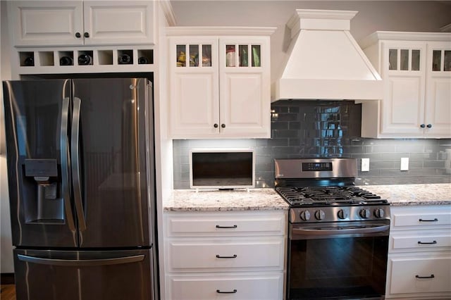 kitchen featuring white cabinetry, stainless steel appliances, glass insert cabinets, and custom range hood