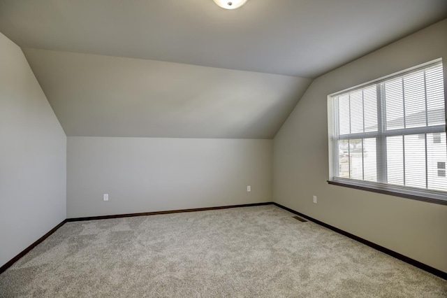 additional living space featuring baseboards, carpet floors, visible vents, and vaulted ceiling