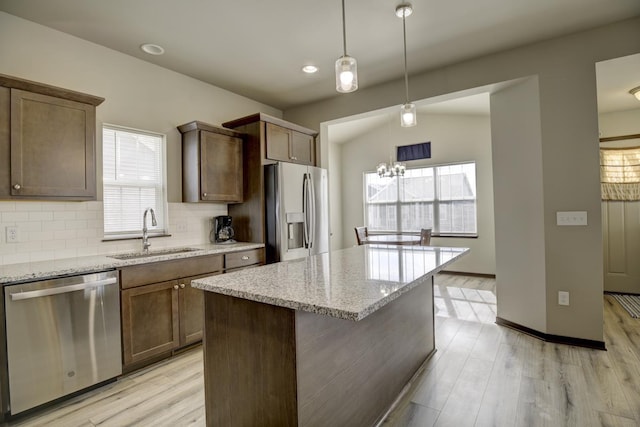 kitchen with tasteful backsplash, stainless steel appliances, light wood-style floors, and a sink