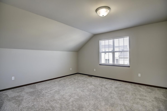 additional living space with visible vents, baseboards, carpet flooring, and vaulted ceiling