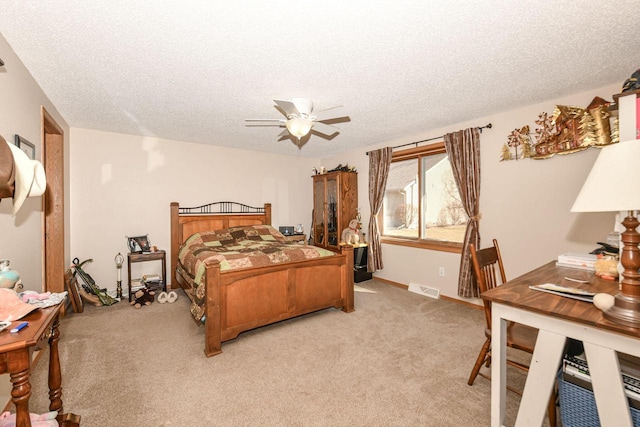 bedroom with visible vents, light colored carpet, a ceiling fan, and a textured ceiling