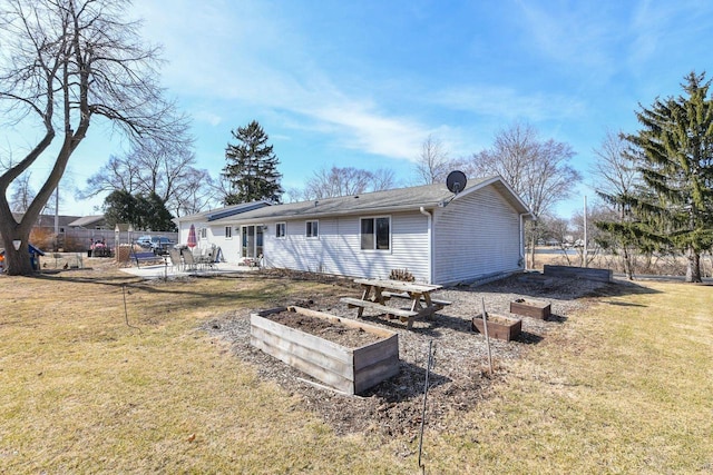 rear view of house with a patio, a lawn, a vegetable garden, and fence