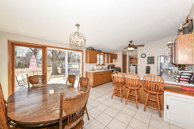 dining space featuring a textured ceiling, washer / dryer, light tile patterned flooring, and ceiling fan with notable chandelier