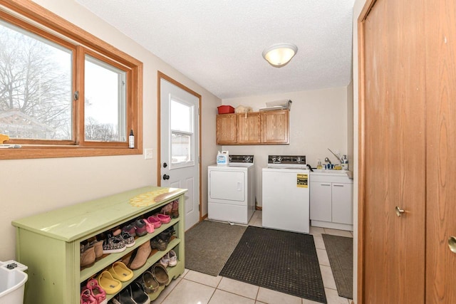 washroom with light tile patterned floors, cabinet space, a sink, a textured ceiling, and washer and dryer