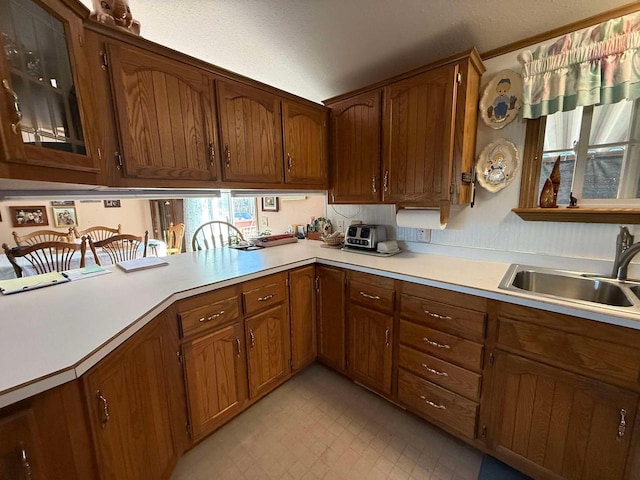 kitchen featuring light countertops, brown cabinetry, light floors, and a sink