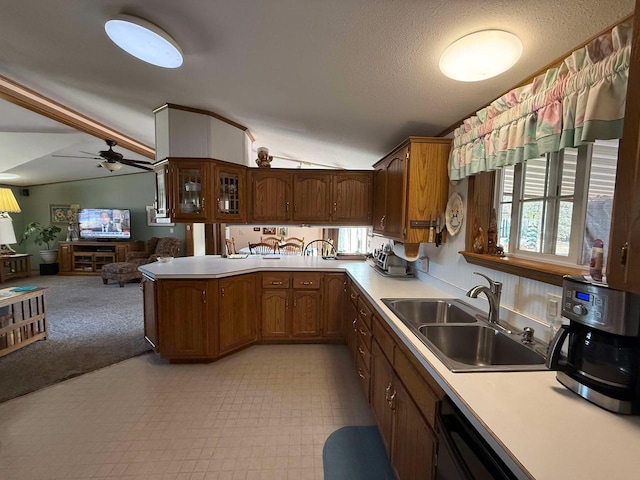 kitchen featuring vaulted ceiling, a peninsula, light countertops, and a sink