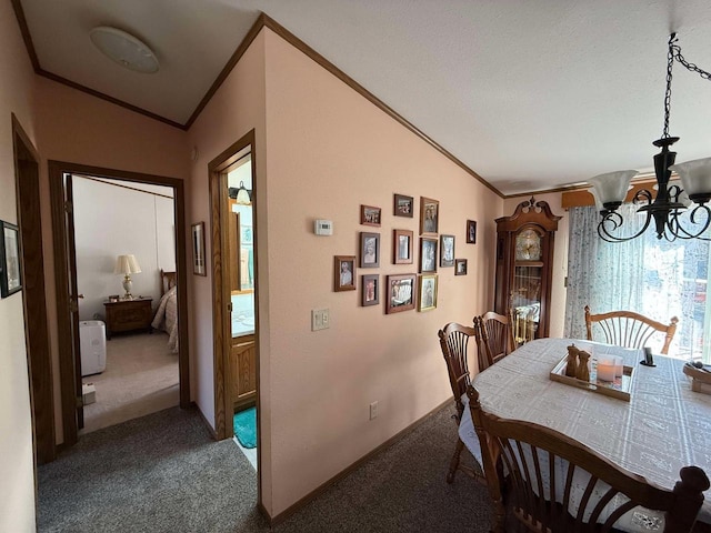 dining area featuring a chandelier, baseboards, crown molding, and carpet