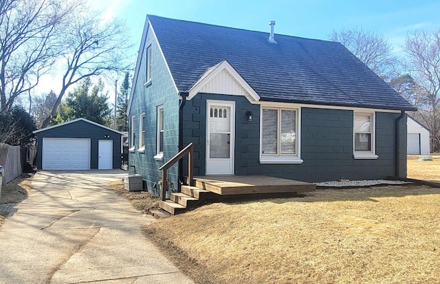 view of front of property with an outbuilding, a front lawn, a detached garage, a shingled roof, and concrete block siding