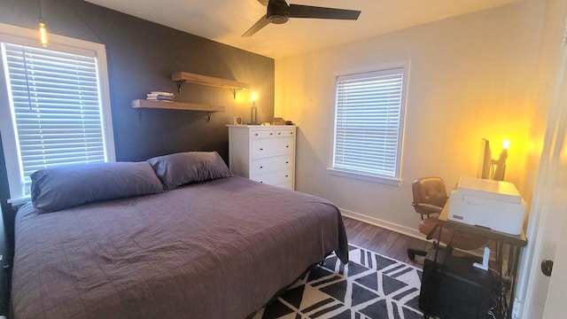 bedroom featuring baseboards, multiple windows, wood finished floors, and a ceiling fan