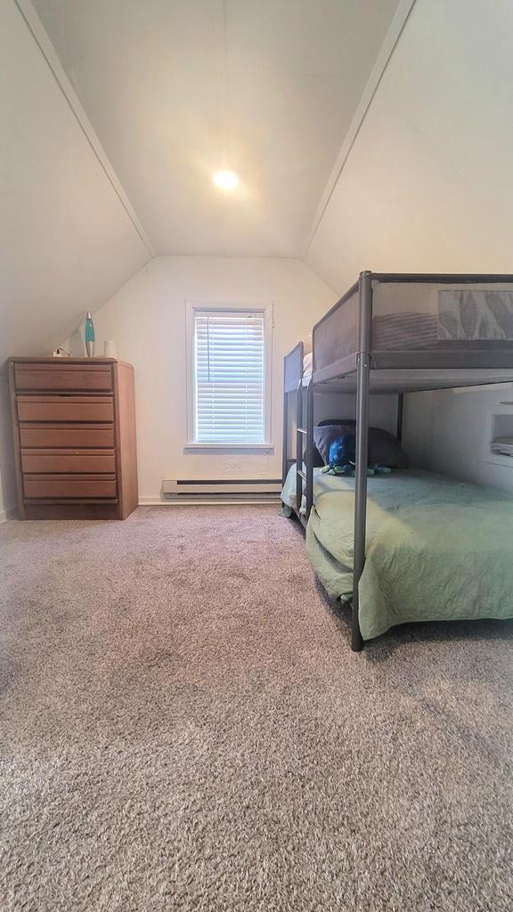 bedroom featuring carpet floors, a baseboard heating unit, and vaulted ceiling